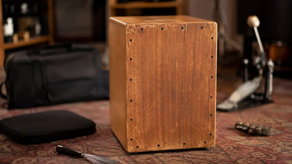 A cajon drum with various accessories like brushes and microphones to enhance sound and performance.