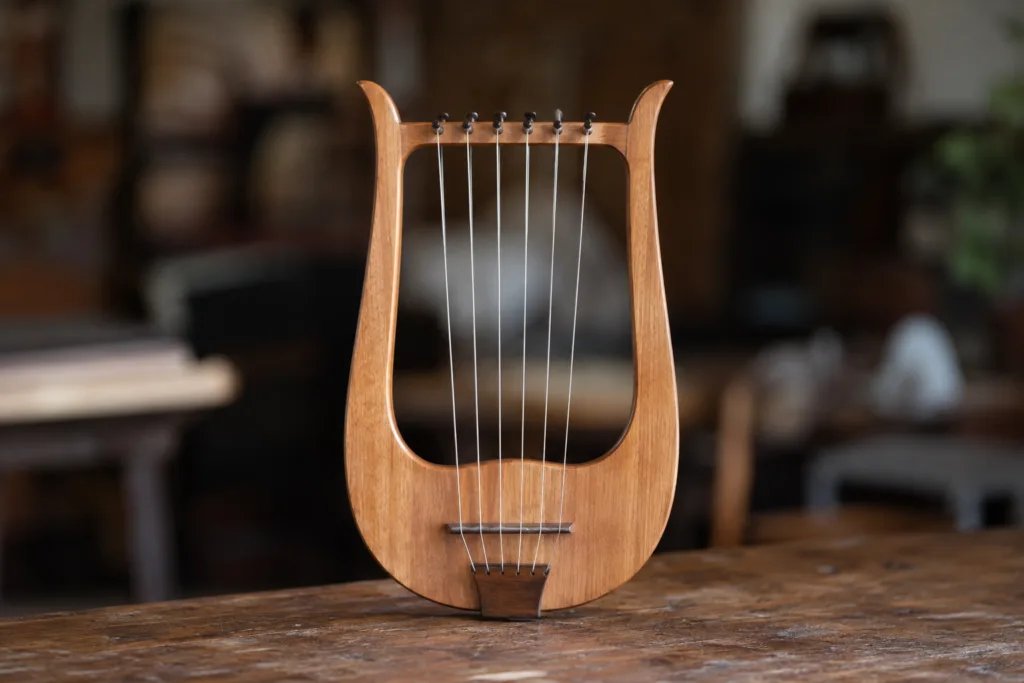 Trossingen Lyre with wooden frame and strings on a rustic table, photographed against a softly blurred indoor background.